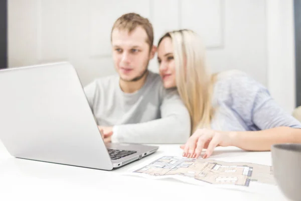 Preciosa pareja joven, utilizando un ordenador portátil y la elección de un nuevo apartamento . — Foto de Stock