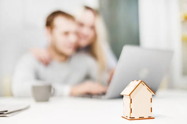 Mooi jong stel, met behulp van een laptop en het kiezen van een nieuw appartement. Indeling van het huis op de voorgrond. — Stockfoto