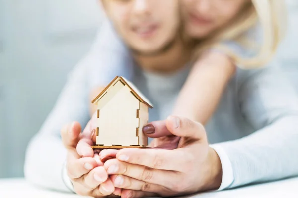 Preciosa pareja joven sosteniendo un diseño de la casa en sus manos extendidas. El concepto de comprar un nuevo apartamento . — Foto de Stock