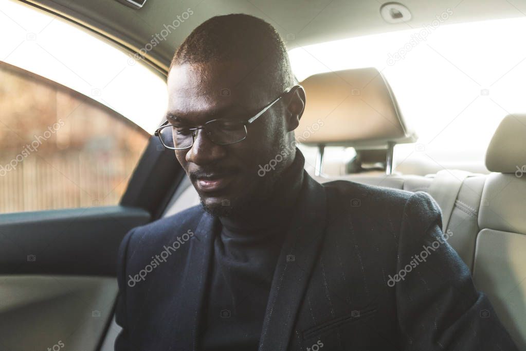 Young business man in the back seat in an expensive car goes to a meeting.