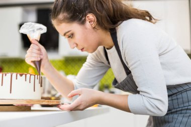 Bir şekerlemeler ahşap bir stand üzerinde beyaz krem bisküvi kek üzerine bir pasta torbası sıvı çikolata sıkır. Ev yapımı pasta kavramı, yemek pastaları.