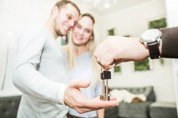 Una encantadora pareja joven obtiene las llaves de su nuevo apartamento de un agente de bienes raíces . — Foto de Stock