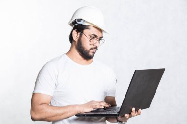 Gözlük ve beyaz güvenlik kask genç Oluşturucu mühendisi, açık bir dizüstü bilgisayar ile standları.