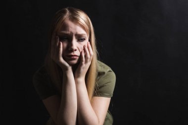 Üzgün genç kadın siyah bir arka planda ağlamaya gidiyor