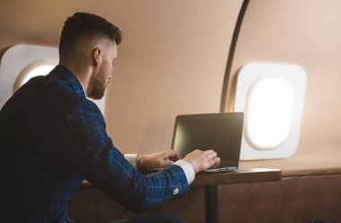 Onun özel jet bir sandalyede otururken bir laptop üzerinde çalışan çekici ve başarılı işadamı.