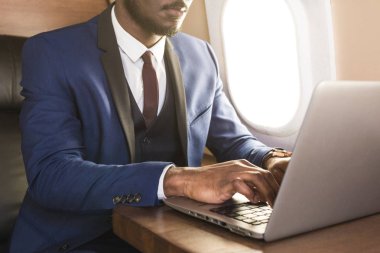 Onun özel jet sandalyede otururken gözlük bir dizüstü bilgisayar üzerinde çalışan çekici ve başarılı Afrikalı Amerikan işadamı.