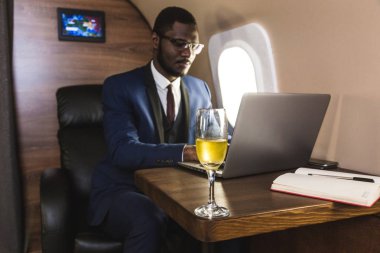 Onun özel jet sandalyede otururken gözlük bir dizüstü bilgisayar üzerinde çalışan çekici ve başarılı Afrikalı Amerikan işadamı.