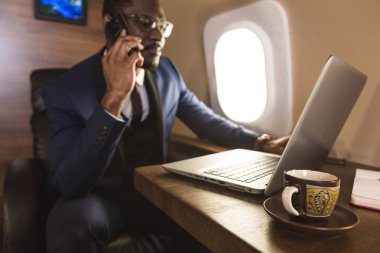 Onun özel iş uçağı sandalyesinde oturup telefonda konuşurken GLASSiES ile genç çekici ve başarılı Afrikalı Amerikan işadamı