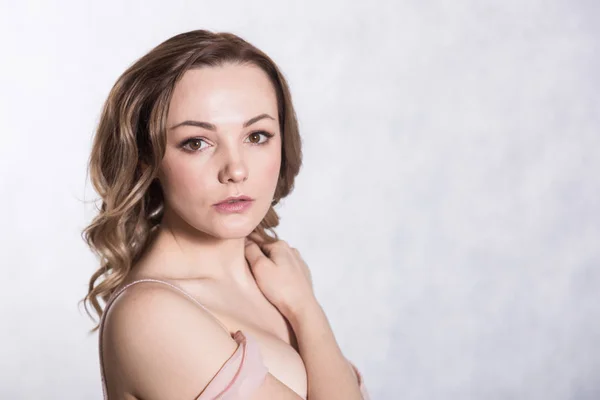 Retrato de hermosa joven elegante mujer en vestido de novia de color rosa pálido con escote grande, sobre un fondo blanco . — Foto de Stock