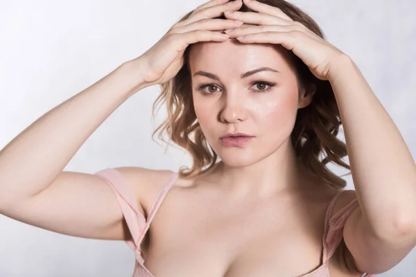 Portret van mooie jonge elegante vrouw in bleke roze trouwjurk met grote halslijn, op een witte achtergrond. — Stockfoto