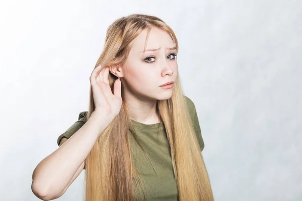 Young woman trying to hear better by attaching his palm to ear.