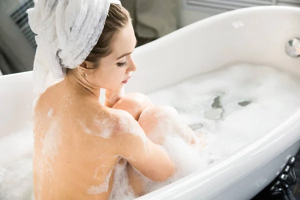 Una giovane ragazza attraente si rilassa in bagno e riposa sullo sfondo di un bellissimo interno leggero. Trattamenti Spa per la bellezza e la salute con la cura della pelle — Foto Stock