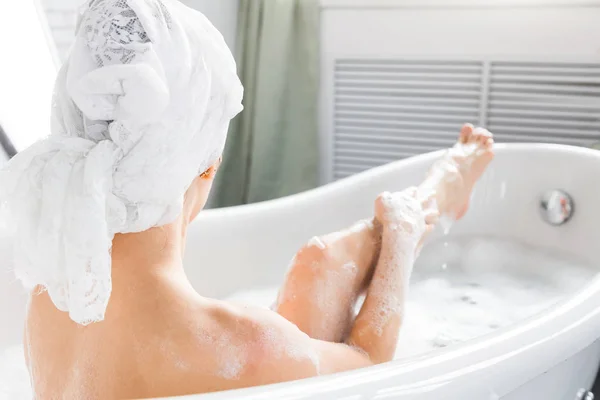 Una giovane ragazza attraente si rilassa in bagno e riposa sullo sfondo di un bellissimo interno leggero. Trattamenti Spa per la bellezza e la salute con la cura della pelle — Foto Stock