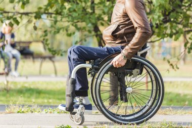 Genç biri tekerlekli sandalyede park yol boyunca rides.