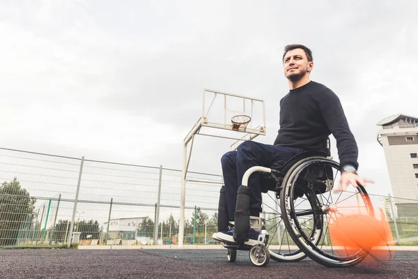 Jonge man in een rolstoel spelen basketbal. — Stockfoto