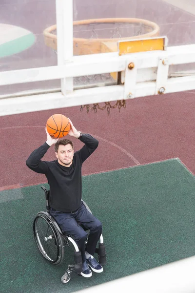 Νεαρός άνδρας σε μια αναπηρική καρέκλα που παίζει μπάσκετ. — Φωτογραφία Αρχείου