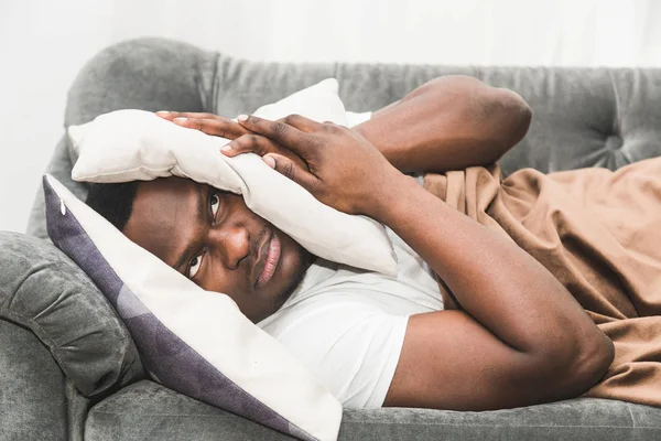 Sleepy guy waking up early after hearing alarm clock signal and does not want to get up.