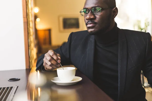 Ung vacker mörkhyade affärs man i ett kafé med en kopp te. — Stockfoto