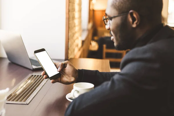 Ung vacker mörkhyade affärs man i ett kafé som pratar på en mobil telefon med en kopp te. — Stockfoto