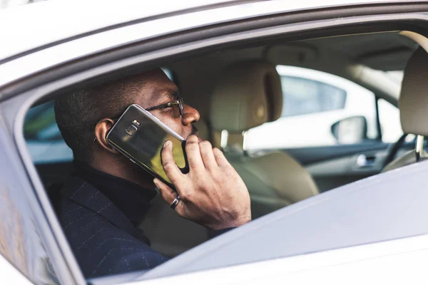 Młody biznesmen mówi na telefon siedzi na tylnym siedzeniu drogiego samochodu. Negocjacje i spotkania biznesowe. — Zdjęcie stockowe
