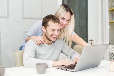 Genç çift onlar mutfak ve dizüstü bilgisayar kullanarak sabah oturuyor. Online alışveriş konsepti. Arka planda modern mutfak.