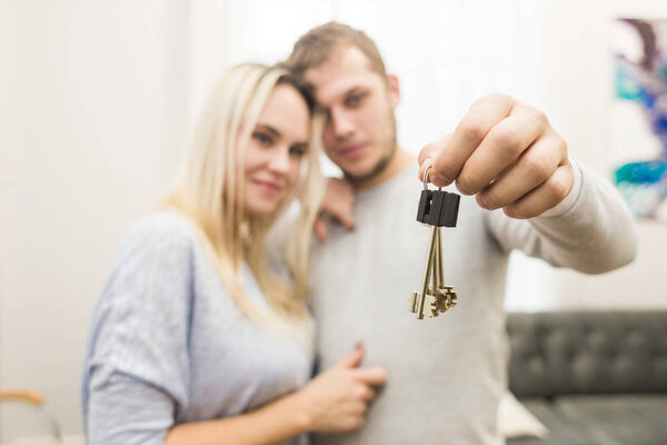 A lovely young couple holds in front of them the keys to their new apartment.