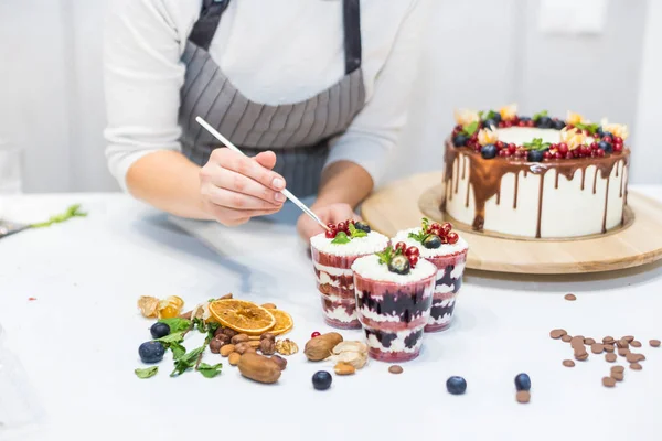 Decoratie van het afgewerkte dessert. Banketbakker bestrooit zoetwaren met geel poeder. Het concept van zelfgemaakte gebak, koken cakes. — Stockfoto