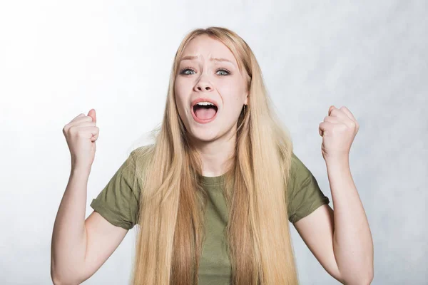 Retrato de mujer alegre aprieta puños con felicidad, posa sobre fondo gris . —  Fotos de Stock