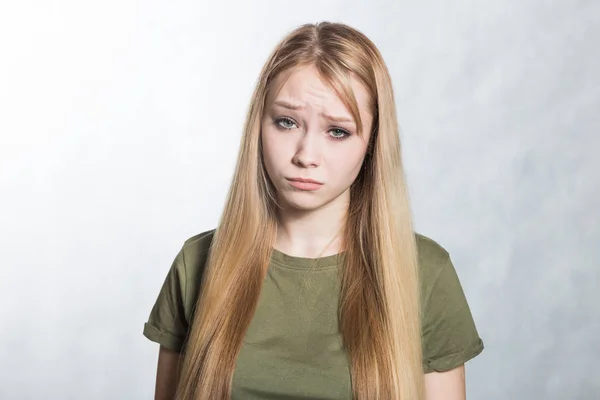 Retrato de una joven y hermosa mujer triste sobre un fondo gris . —  Fotos de Stock