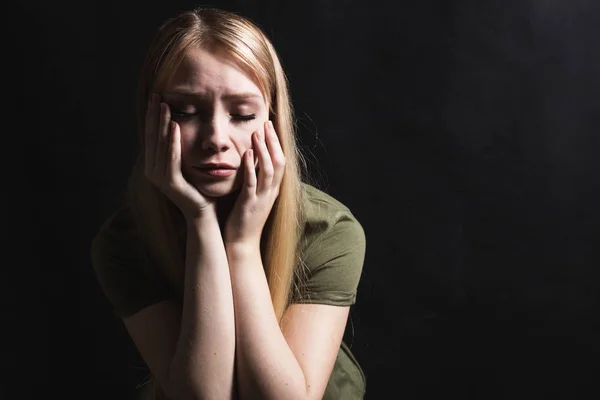 Sad young woman going to cry in a black background — Stock Photo, Image