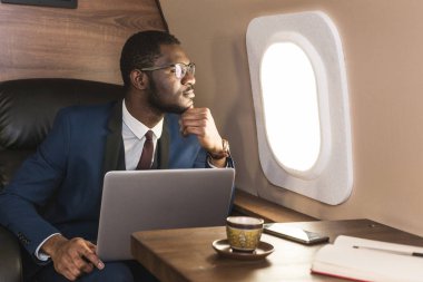 Onun özel jet sandalyede otururken gözlük bir dizüstü bilgisayar üzerinde çalışan çekici ve başarılı Afrikalı Amerikan işadamı.