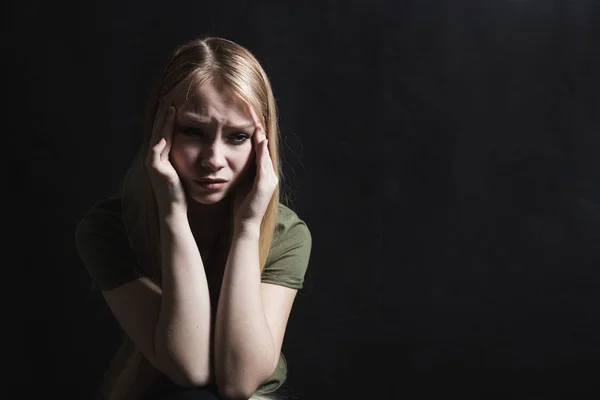Sad young woman going to cry in a black background — Stock Photo, Image