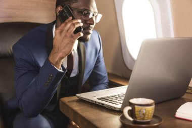 Onun özel iş uçağı sandalyesinde oturup telefonda konuşurken GLASSiES ile genç çekici ve başarılı Afrikalı Amerikan işadamı