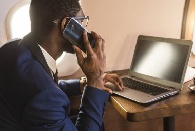 Onun özel iş uçağı sandalyesinde oturup telefonda konuşurken GLASSiES ile genç çekici ve başarılı Afrikalı Amerikan işadamı