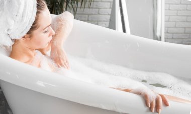 Genç çekici bir kız banyoda rahatlatır ve güzel bir ışık iç zemin karşı oturmaktadır. Cilt Bakımı ile güzellik ve sağlık için spa uygulamaları