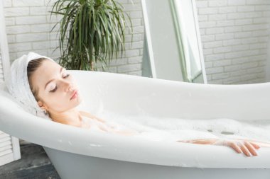 Genç çekici bir kız banyoda rahatlatır ve güzel bir ışık iç zemin karşı oturmaktadır. Cilt Bakımı ile güzellik ve sağlık için spa uygulamaları