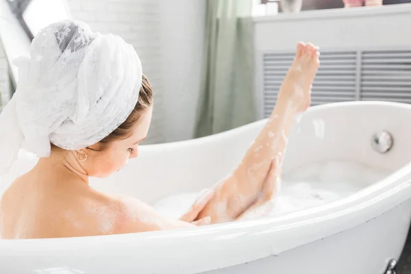 Une jeune fille séduisante se détend dans la salle de bain et repose sur le fond d'un bel intérieur lumineux. Soins spa pour la beauté et la santé avec soin de la peau — Photo