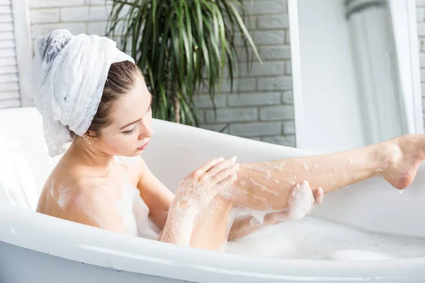 Uma jovem garota atraente relaxa no banheiro e descansa contra o pano de fundo de um belo interior de luz. Tratamentos de spa para beleza e saúde com cuidados com a pele — Fotografia de Stock