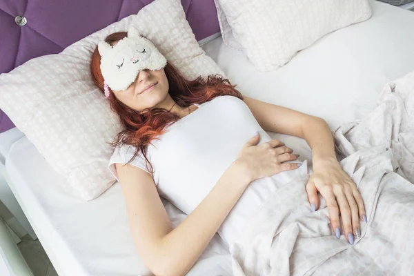 Une jolie jeune fille dormant dans son lit sous un masque de sommeil. Vue d'en haut — Photo