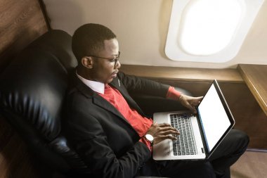 Onun özel jet sandalyede otururken gözlük bir dizüstü bilgisayar üzerinde çalışan çekici ve başarılı Afrikalı Amerikan işadamı