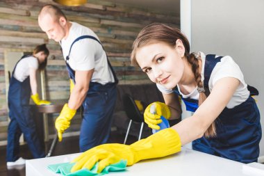 İş sırasında profesyonel ekipmanlarla temizlik hizmeti. Profesyonel mutfak temizliği, kanepe kuru temizleme, pencere ve yer silme. Erkek ve kadın üniformalı, tulumlu ve lastik eldivenli.