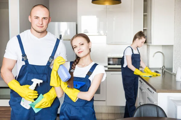 Reinigungsservice mit professionellem Gerät während der Arbeit. Professionelle Küchenreinigung, Sofa-Trockenreinigung, Fenster- und Fußbodenwäsche. Männer und Frauen in Uniform, Overalls und Gummihandschuhen — Stockfoto