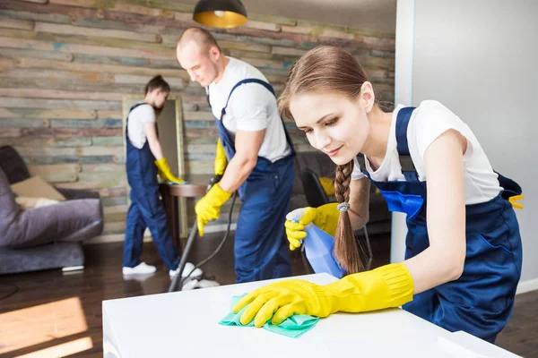 Serviço de limpeza com equipamento profissional durante o trabalho. limpeza kitchenette profissional, sofá limpeza a seco, janela e lavagem de piso. homem e mulher de uniforme, macacão e luvas de borracha — Fotografia de Stock