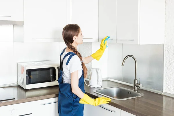 Servicio de limpieza con equipo profesional durante el trabajo. limpieza profesional de la cocina, limpieza en seco del sofá, lavado de ventanas y suelos. hombres y mujeres en uniforme, monos y guantes de goma —  Fotos de Stock