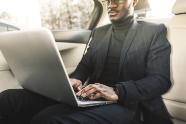 Bir iş kıyafeti adam deri iç ile pahalı bir araba salonda laptop yazmak.