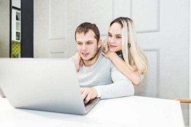 Genç çift onlar mutfak ve dizüstü bilgisayar kullanarak sabah oturuyor. Online alışveriş konsepti. Arka planda modern mutfak.