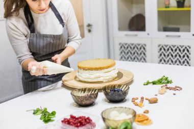 Pastanın üstüne krema sıkan bir pasta torbasıyla pastacı. Ev yapımı hamur işi, kek pişirme....