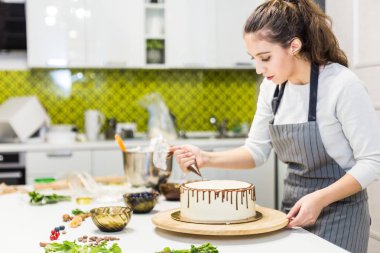 Bir şekerlemeler ahşap bir stand üzerinde beyaz krem bisküvi kek üzerine bir pasta torbası sıvı çikolata sıkır. Ev yapımı pasta kavramı, yemek pastaları.