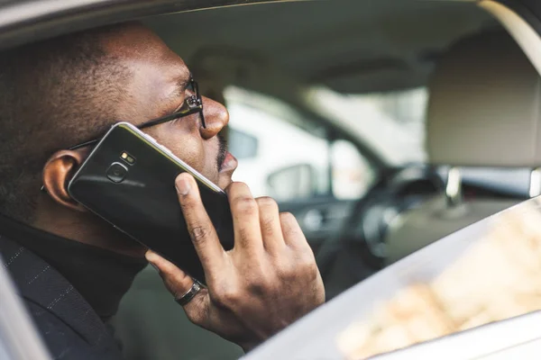 Młody biznesmen mówi na telefon siedzi na tylnym siedzeniu drogiego samochodu. Negocjacje i spotkania biznesowe. — Zdjęcie stockowe