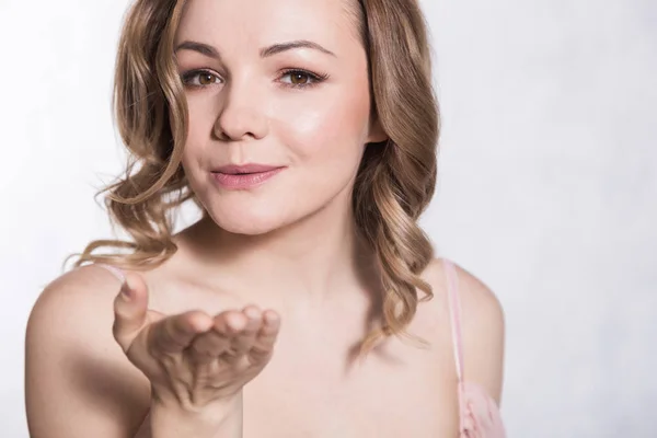 Portret van mooie jonge elegante vrouw in bleke roze trouwjurk met grote halslijn, op een witte achtergrond. — Stockfoto